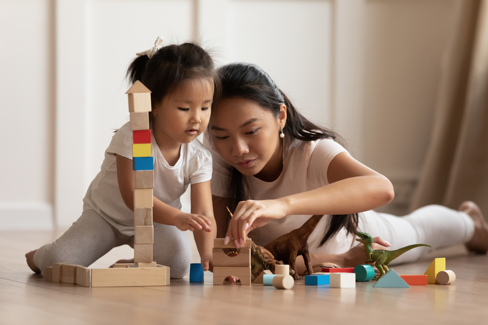 Kid playing with Montessori toys in the supervision of Mom.